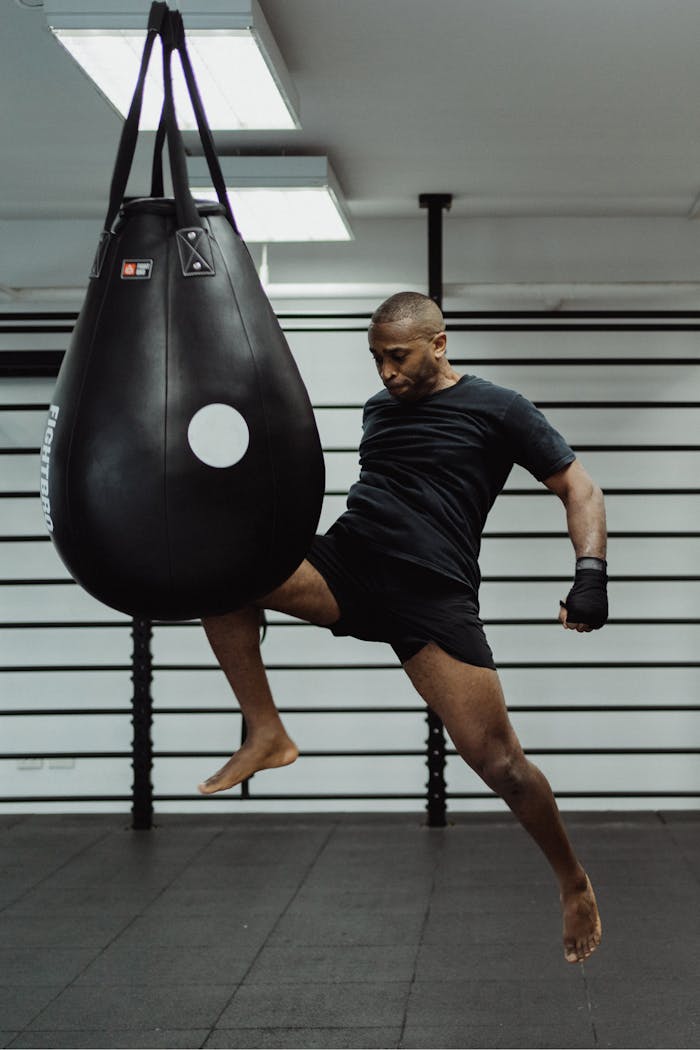 Athlete delivers a powerful kick to a punching bag in an intense training session.